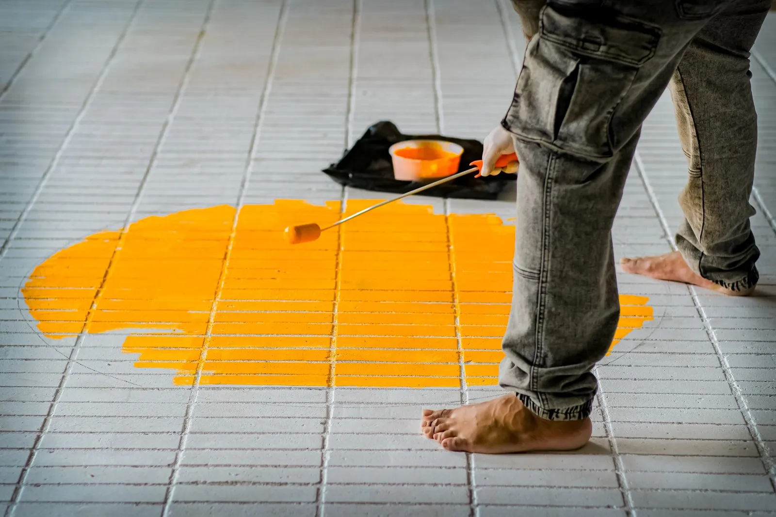 Application d'une peinture carrelage blanche au rouleau sur un mur de salle de bains claire.