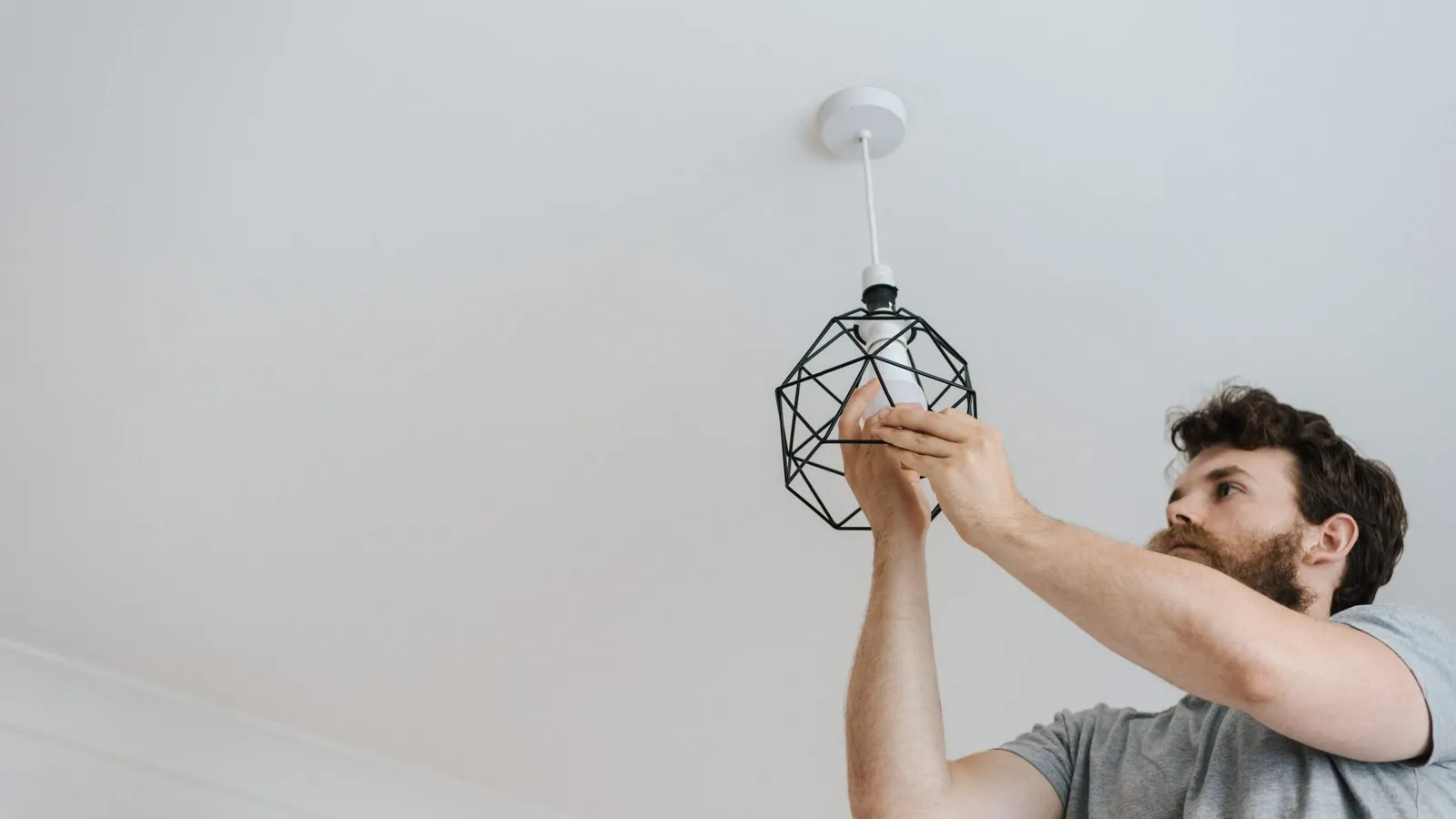 Plafonnier rond blanc fixé au plafond d'une salle de bain moderne, près d'une douche en verre.
